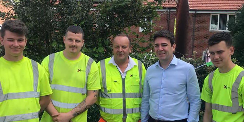 Manchester Mayor Andy Burnham underlined his green credentials on Wednesday 15th May 2019 by officially opening a health community allotment in Stockport. The allotment project in Woodley first took roots about two years ago when local couple, David and Julie Ashton, were helped through their own medical problems by their GPs Health Champions. They were so impressed at what the Alvanley Family Practice Health Champions were doing that they decided that wanted to give something back. As keen gardeners they wanted to use the skills and experience they had, and with the backing of their fellow Champs, they hit on the idea of a community allotment and so the project began. Stockport Council pitched in by giving them, for free, a much-neglected allotment plot and The George Cox Foundation initially created the basic infrastructure for the allotments out of some very overgrown land. The foundation was approached again this year by the residents for some further help and it was seen as a great opportunity to provide on-the-job training for our Apprentices. The requirement was to provide pedestrian access around the site using a combination of paving and tarmac. This gave the apprentices the chance to learn about levels, designs, block paving and surfacing techniques. The allotment committee have given fantastic feedback regarding their attitude, commitment to the project and the finished result. David commented "It's a great space for local people to use and is adding to the real sense of community that we already have in Woodley thanks to the Health Champions. You don't have to be a patient of the Alvanley Family Practice to come here everyone is welcome. Officially opening the allotment Andy Burnham said "The Alvanley Family Practice with their Health Champions are showing us the future of primary care. We love the NHS but for it to survive in the future it needs to provide more than medication and projects like this community allotment show just what can be achieved." Alvanley Family Practice's Dr Mark Gallagher said "Today is not about the practice but rather about our amazing community. We have nothing but pride and admiration for our wonderful volunteers who, by freely giving their time and dedication, are creating something for everyone to be a part of." Plans for the allotment include a multi-purpose large shed, with plumbed in facilities, which will be used for a variety of Champion run community activities. This is being funded by a £10,000 grant from Stockport Council's Local Fund.